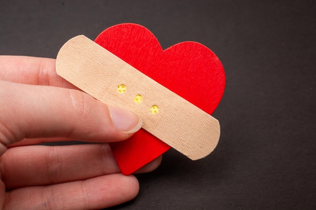 Heart with medical bandage plaster in hand Relationship problems concept