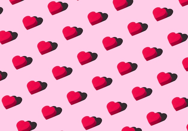 Hearts background. Colored ornament pattern from cut out red hearts on a pink background. Love, romance, wallpaper, postcard minimal concept