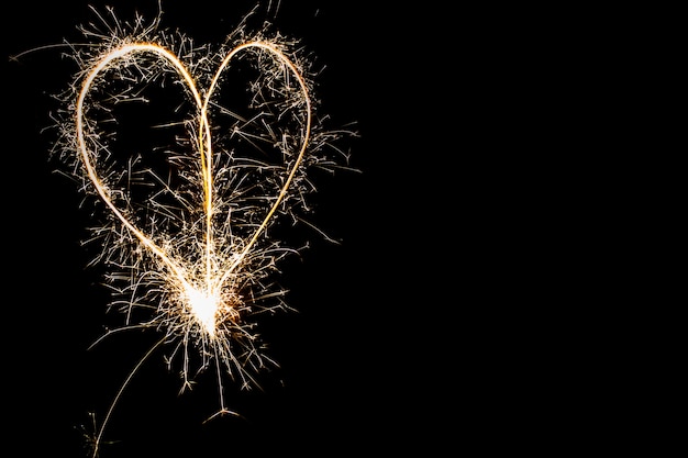 Hearts on a dark background drawn by a sparkler