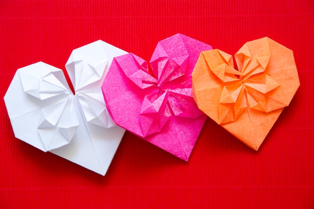 Hearts made of paper origami on red cardboard Background for Valentines day