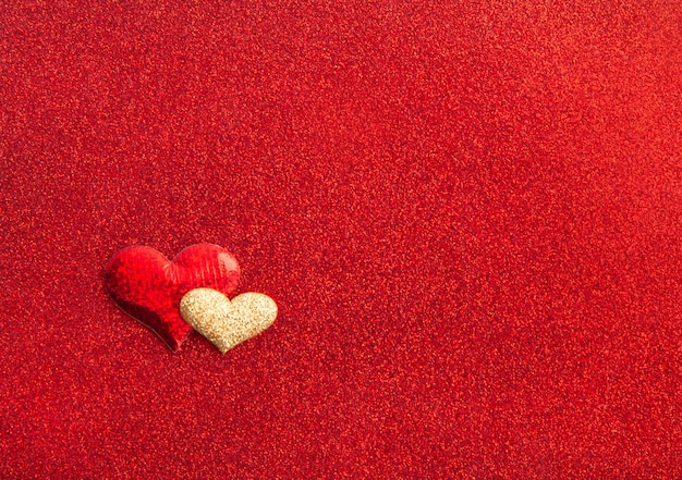 Hearts red and gold on red textured shiny background, holiday concept, top view