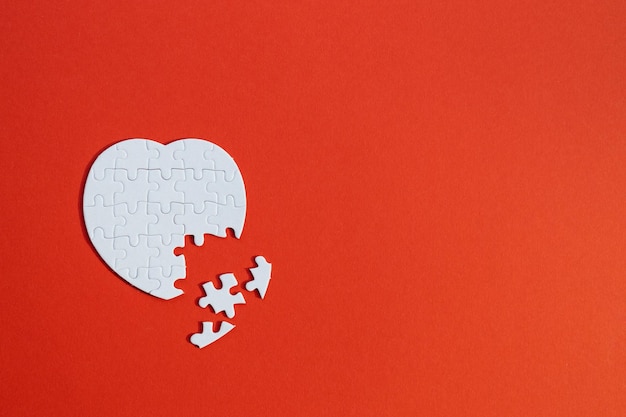 Heartshaped jigsaw puzzle on color background