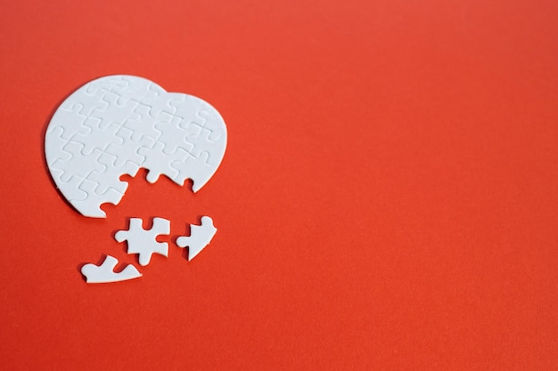 Heartshaped jigsaw puzzle on color background