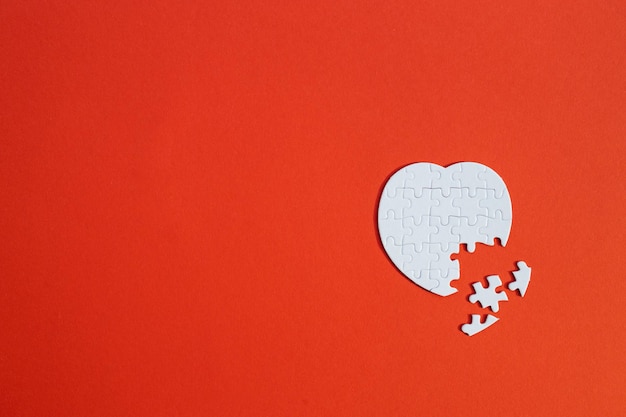 Heartshaped jigsaw puzzle on color background