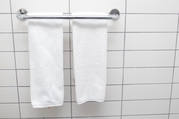 Heated towel rail on bathroom wall. White towels drying on a heated towel rail.