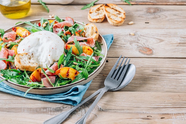 Heathy summer salad with grilled peach arugula ham and burrata