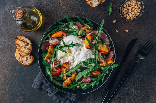 Heathy summer salad with grilled peach arugula ham and burrata