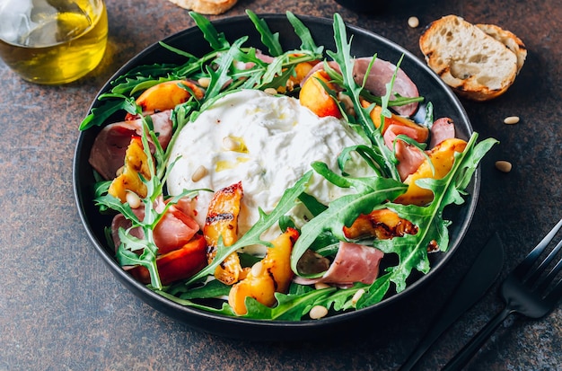 Heathy summer salad with grilled peach arugula ham and burrata