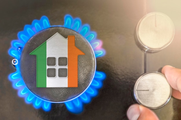 Heating season or gas use in Ireland Concept model of a house stands near the flame of a gas boiler on a black background The cost of using natural gas in Ireland