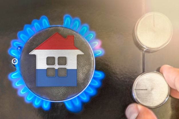 Heating season or gas use in Netherlands Concept model of a house stands near the flame of a gas boiler on a black background The cost of using natural gas in Netherlands