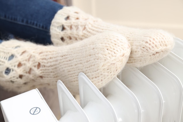 Heating season woman warms her legs with heater