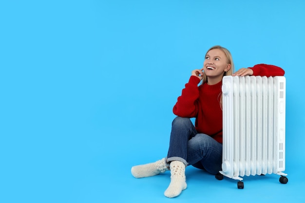 Heating season woman with heater on blue background