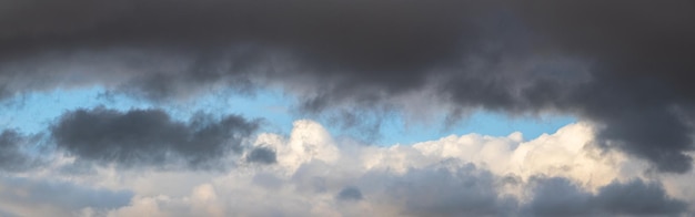 A heavy dark cloud hangs over a white cloud in a blue sky