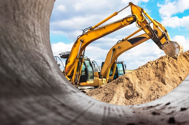 Heavy excavator at the construction site View of the excavator through the iron pipe Construction equipment for earthworks Quarry excavator