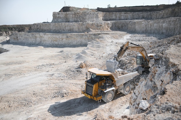 Photo heavy mining truck and excavator closeup against the background of the panorama of a limestone quarry