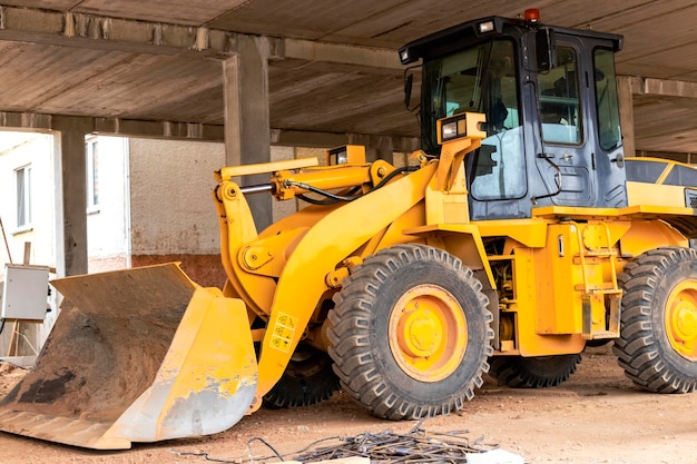 Heavy wheel loader with a bucket at a construction site Closeup Equipment for earthworks transportation and loading of bulk materials earth sand crushed stone