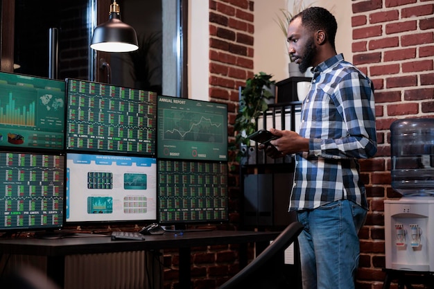 Photo hedge fund trading company agent having touchscreen tablet device analyzing stocks buy and sell price ranges. adult broker stand near multi monitor workstation while reviewing financial data.