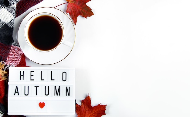 Hello autumn concept Cup of hot espresso coffee and fallen red leaves on white background Warm plaid and drink for cold weather