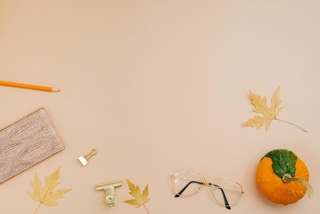 Hello autumn concept Workplace with fallen leaves pumpkin notepad pencils student glasses schoolgirl