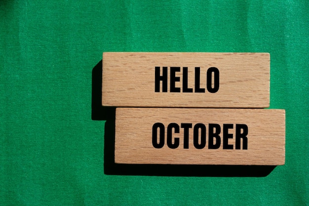 Photo hello october message written on wooden blocks with green background conceptual hello october symbol copy space