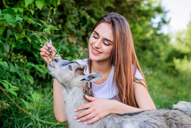 Hello pets woman vet feeding goat farm and farming concept Animals are our friends happy girl love goat village weekend summer day Love and protect animals contact zoo veterinarian lamb goat