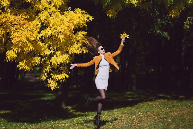 Hello September a happy young woman in a white dress outdoors in a city park rejoices in autumn