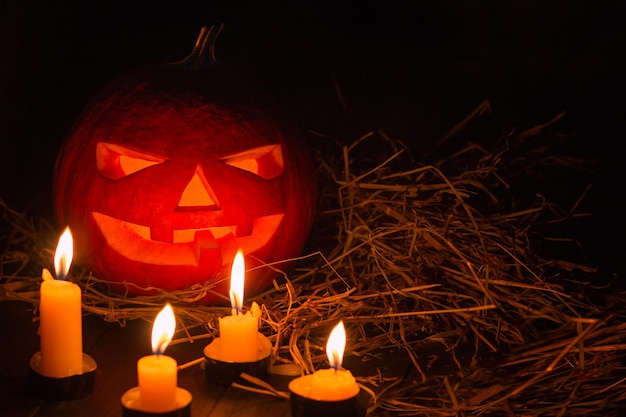 Helloween pumpkin with candles on black background. Big spooky helloween symbol