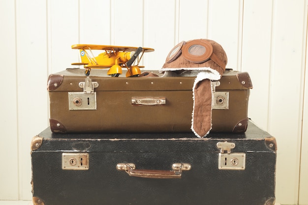 Helmet pilot and toy yellow metal plane Two old retro suitcases White wood Vintage tinting