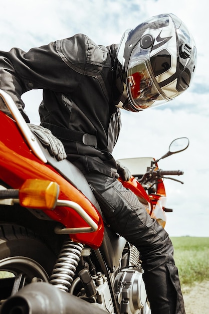 Helmeted biker sitting on motorcycle looking at rear wheel closeup