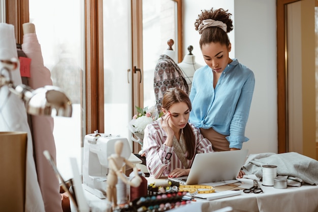 Help each other with the project. Close-up of two young attractive women working on new design project. African young woman in the foreground and caucasian one at the background