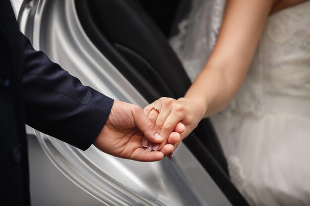 Help for wedding couple in love. Bride and groom holding hands with engagement ring