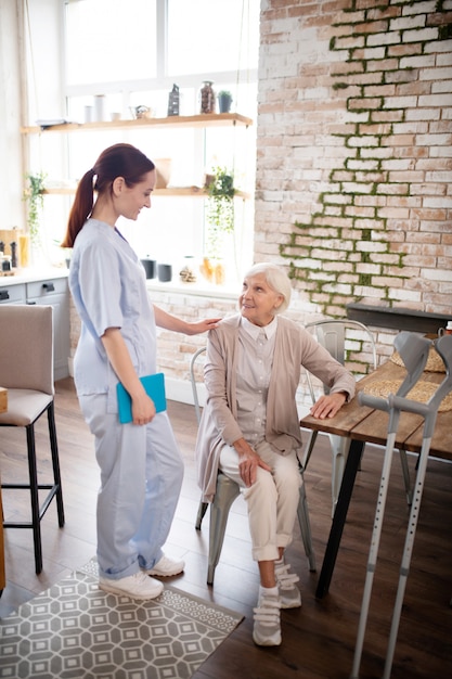 Helpful nurse wearing uniform talking to patient