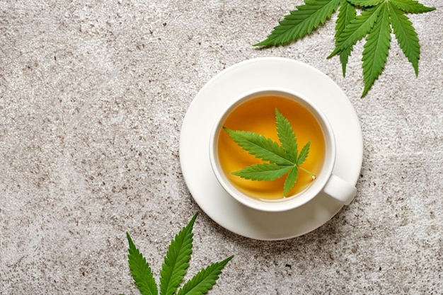 Hemp herbal tea and leaves on gray background Calming drink concept