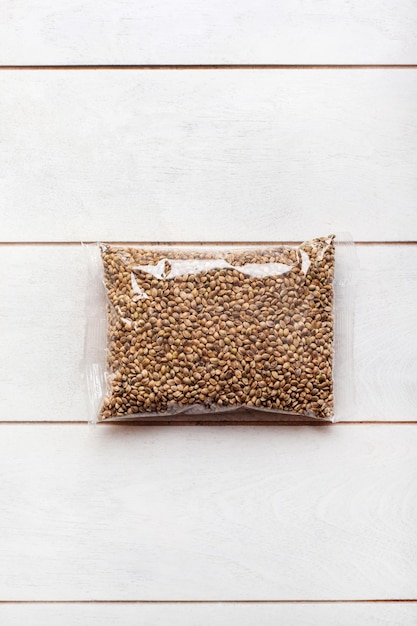 Hemp seeds in transparent packaging on a light wooden background mockup