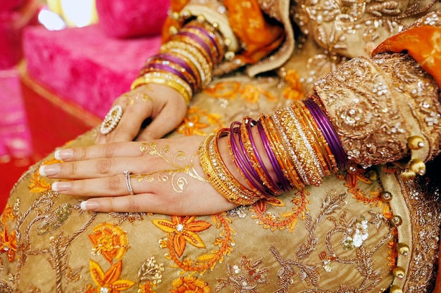 Henna party indian wedding details bride hands with rings bracelets and golden henna close up