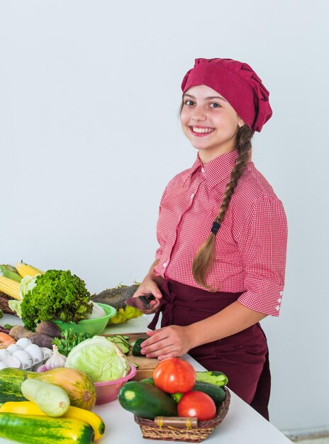 Her new hobby fresh raw vegetables time to eat happy child cooking in kitchen healthy and organic food only full of vitamins kid wear chef uniform and hat teen girl preparing meal