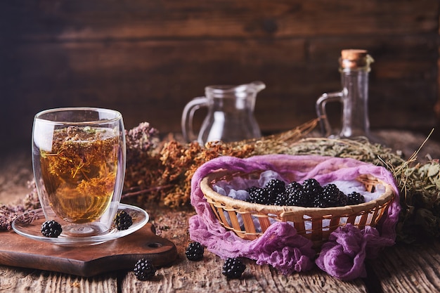 Herbal, flower tea and blackberries on wood