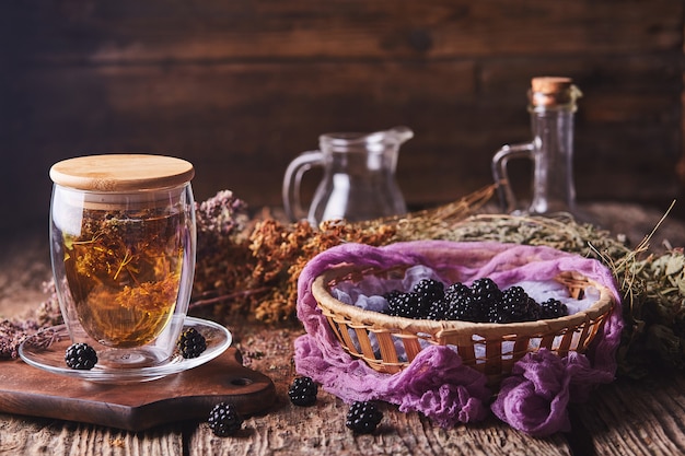 Herbal, flower tea and blackberries on wood