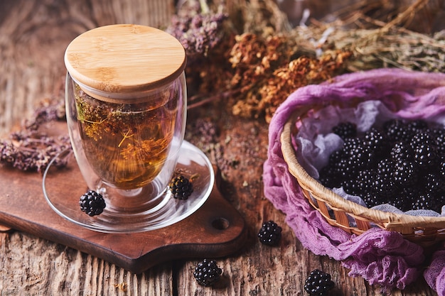 Herbal, flower tea and blackberries on wood