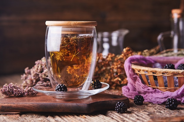 Herbal, flower tea and blackberries on wood