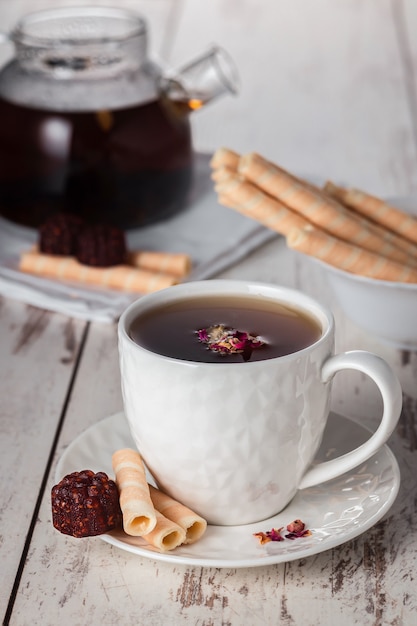 Herbal fruit tea with raspberry marmalade and wafer rolls, tea still life vertical