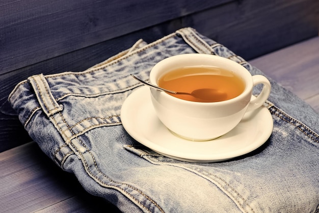 Herbal green or black whole leaf Mug filled boiling water and tea bag on blue jeans background Healthy habits Tea time concept Cup mug hot water and bag of tea Process tea brewing in ceramic mug