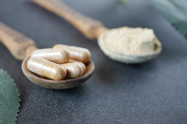 Herbal medicine capsule and powder on a spoon