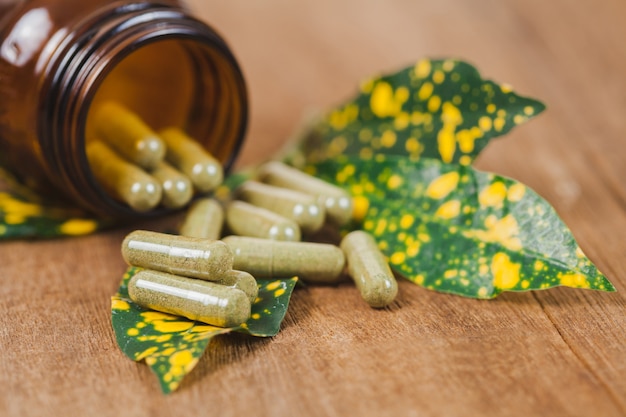 Herbal medicine capsules spilling out of a bottle ,soft focus.