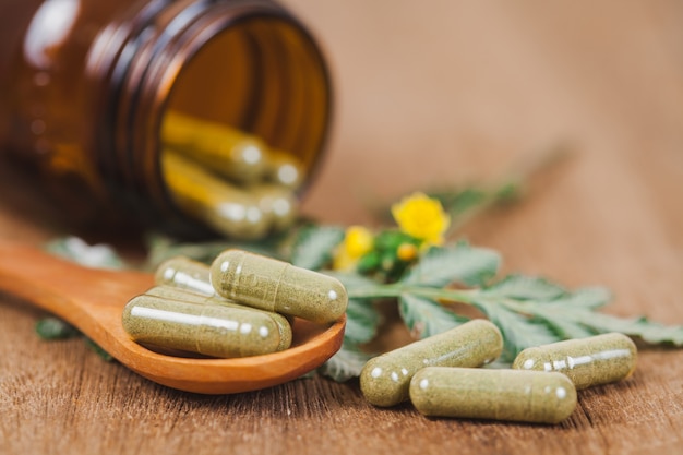 Herbal medicine capsules spilling out of a bottle