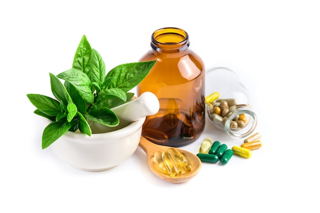 Herbal medicine from green leaf herb, pill, tablet, capsule, drug and vitamin in glass and wooden spoon 