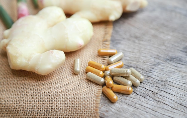 Photo herbal supplement in capsules with young ginger on wooden table for healthy medicine living