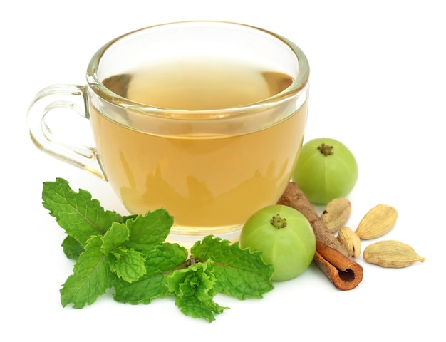 Herbal tea in a cup with different herbs over white background