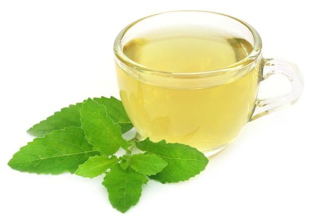 Herbal tea in a cup with tulsi leaves over white background