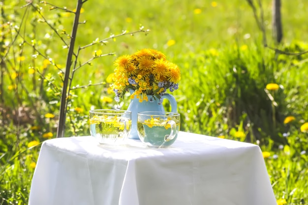 Herbal tea in a glass cup Dandelion flowers in ceramic jug